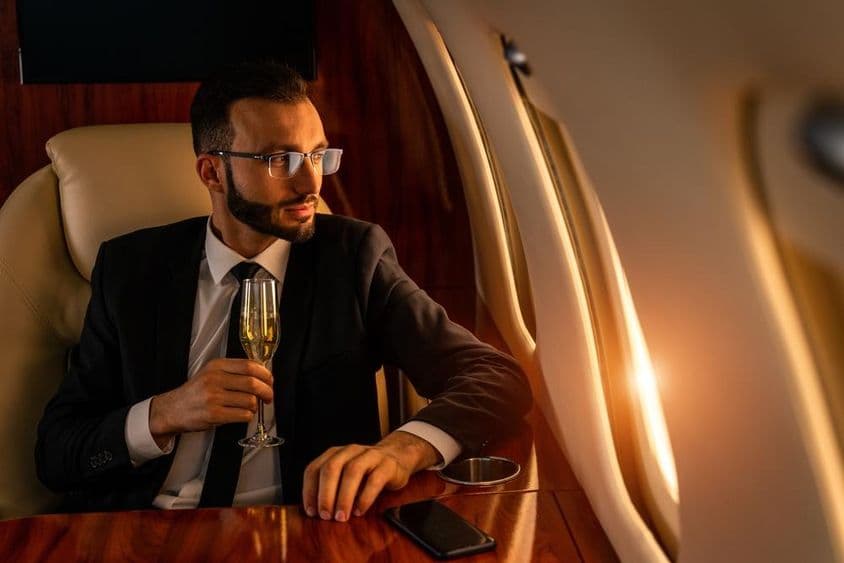 Biznismen si užíva šampanské na súkromnom lietadle