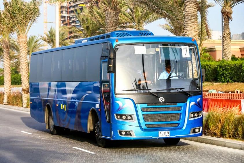 Modrý autobus v Dubaji s palmami v pozadí.