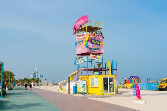 Vitajte na Dubai Kite Beach, značenie, Burj Al Arab v pozadí, v popredí bežecká dráha a piesočná pláž.