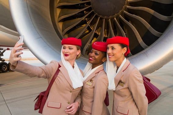 Traja letušky Emirates si robia selfie pred motorom lietadla Emirates.