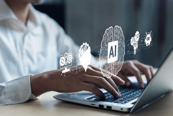 Projekcia nad notebookom zobrazujúca AI mozog a ďalšie prvky. Ľudská ruka pracuje na počítači.