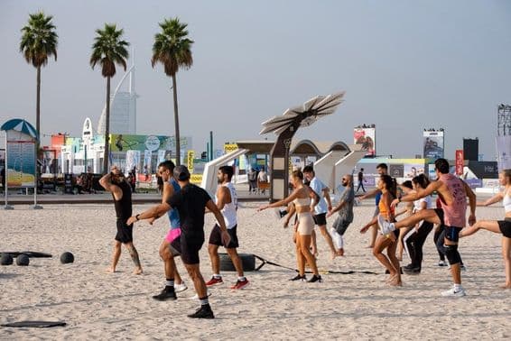 Skupina ľudí cvičí na piesočnej pláži počas Dubai Fitness Challenge.