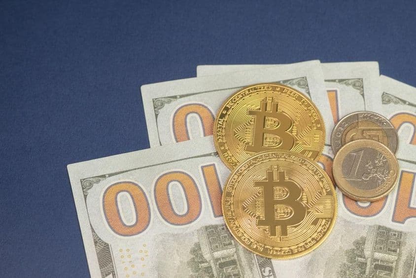 Americký dolár nad bitcoin mincami vedľa 1 euro mince