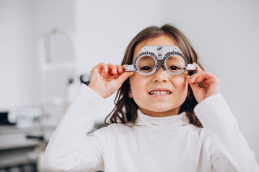 Zrakovo postihnuté dievča nosiace skúšobné okuliare u optika.