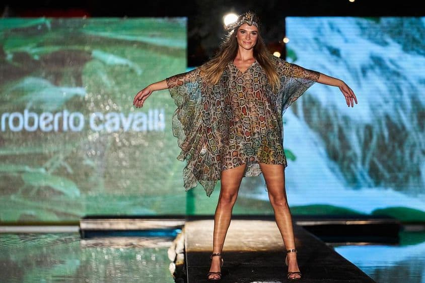 Tabuľa Roberto Cavalli v pozadí, v popredí ženská postava v šatách Roberto Cavalli na móle.