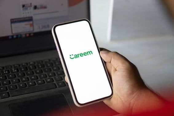Ruka drží telefón s aplikáciou Careem, v pozadí viditeľný zápisník.