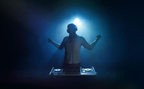 Osoba stojí za DJ stanovišťom.