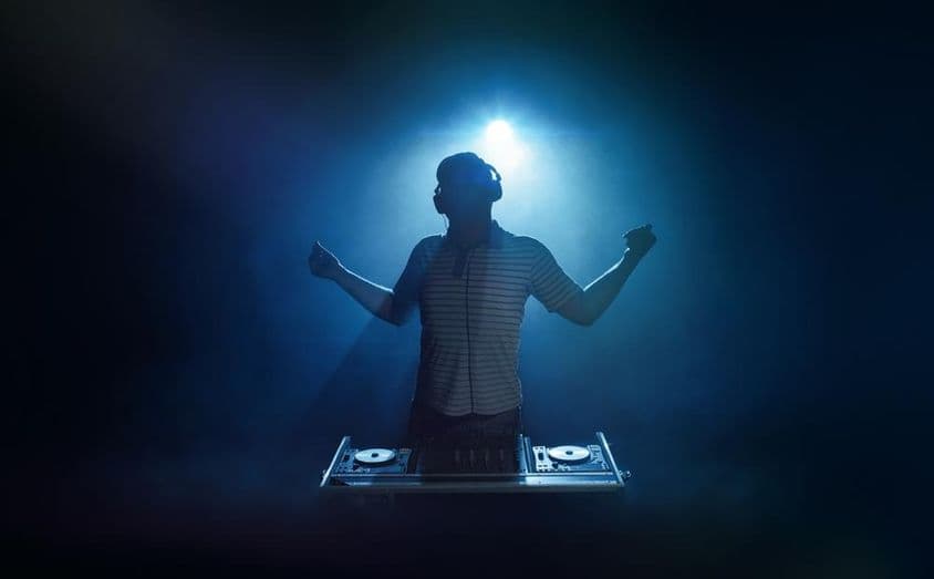 Osoba stojí za DJ stanovišťom.