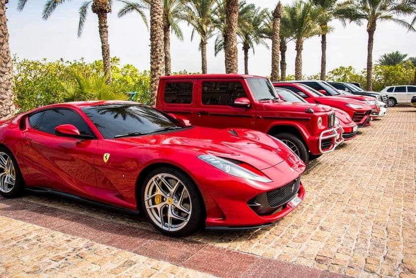 Červené luxusné autá zoradené v Dubaji, vrátane Ferrari, Porsche, Mercedes.