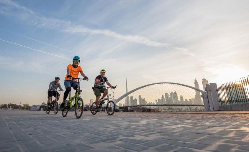 Cyklisti s prilbami pred Burj Khalifa.