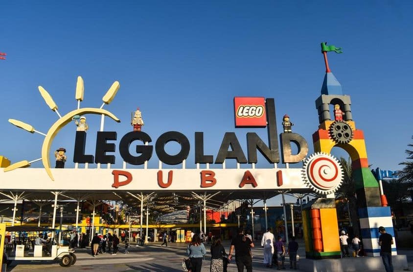 Vstup do LEGOLAND Dubai s ľuďmi a golfový vozík vpredu.