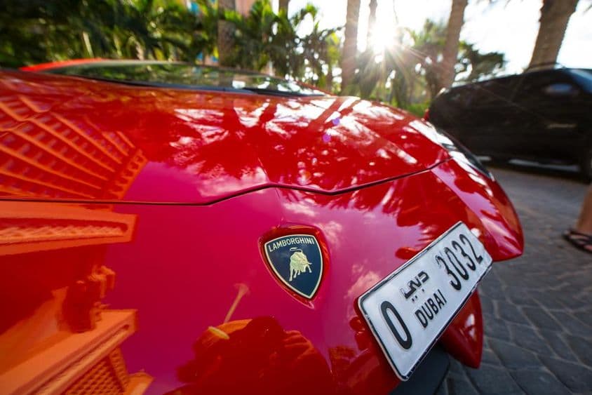Predná časť červeného Lamborghini, ukazujúca štvormiestnu dubajskú poznávaciu značku.