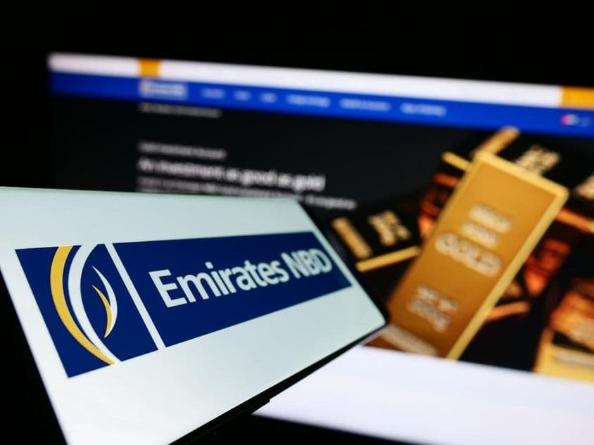 Emirates NBD nápis v popredí, na pozadí zlatá investičná tehla.