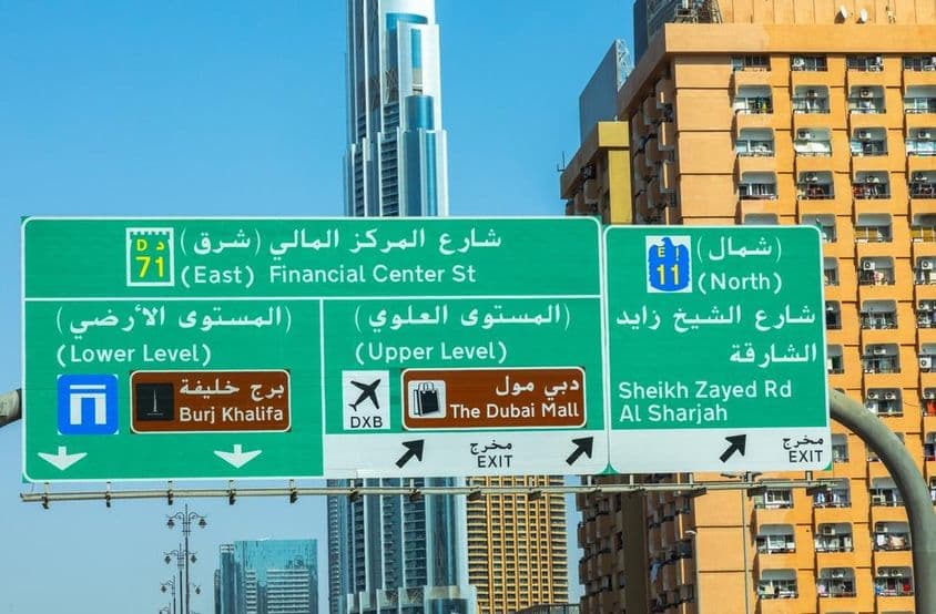 Dubajské mrakodrapy v pozadí, dopravná značka v popredí.