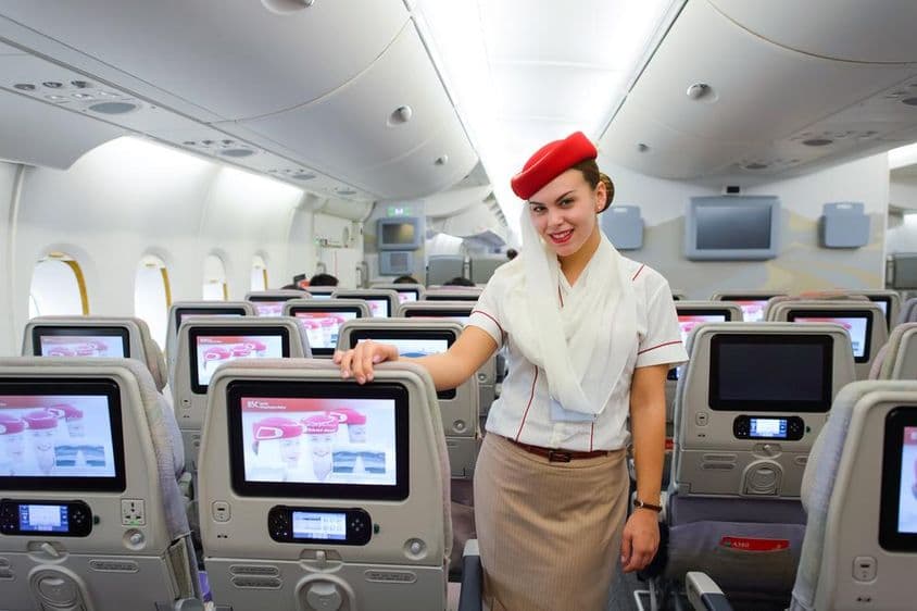 Interiér lietadla Emirates s letušku v popredí.