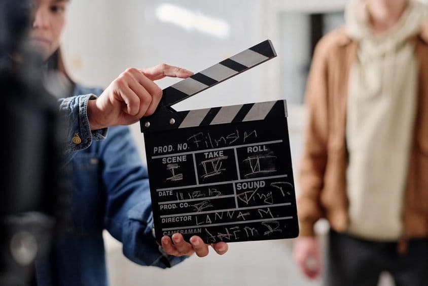 Klapka na filmovanie s kriedovým nápisom, dvaja ľudia vedľa nej.