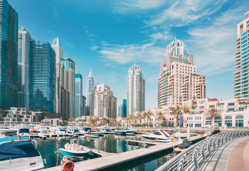Panoráma Dubaja s prístavom, člnmi a mrakodrapmi v pozadí.