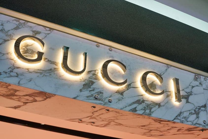 Gucci nápis v osvetlených písmenách na fasáde steny.