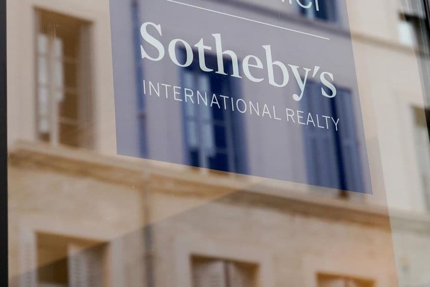 Nápis Sotheby's viditeľný na prednej časti budovy, na priehľadnej tabuli.