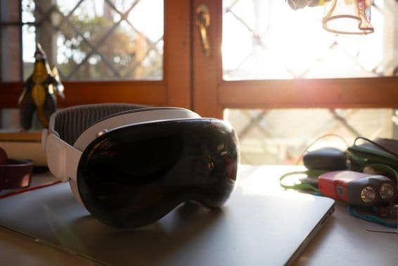 Apple Vision Pro ležiaci na notebooku na stole.