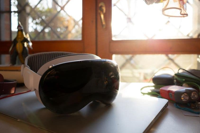 Apple Vision Pro ležiaci na notebooku na stole.