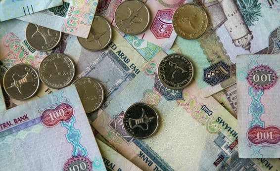 Dubai papierová mena roztrúsená na stole s 1 dirhamovými mincami hore.