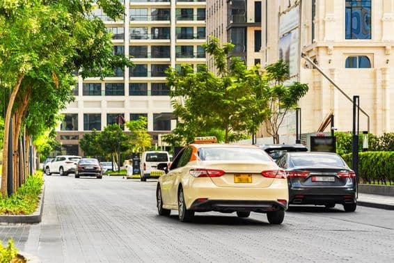 Autá na cestách v Dubaji, taxík v popredí, domy v pozadí.