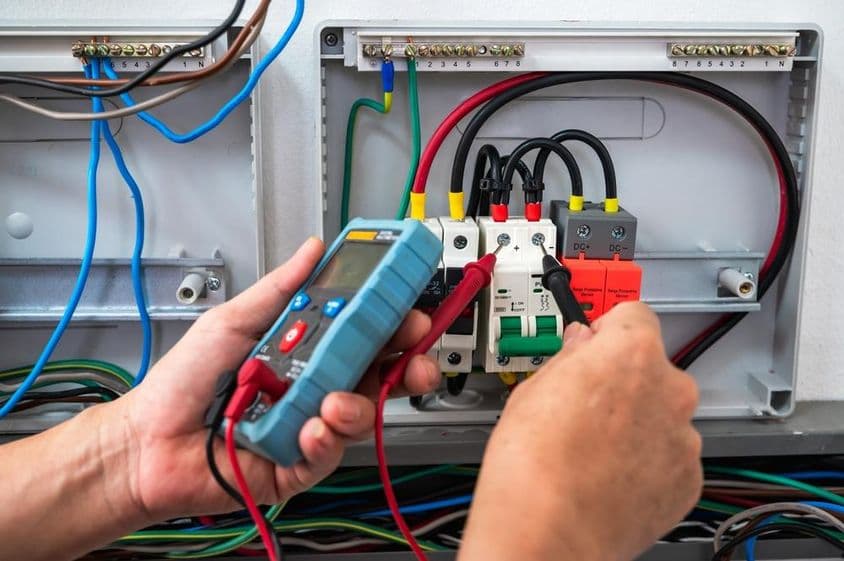 Elektrikár kontroluje zdroj energie s meračom.