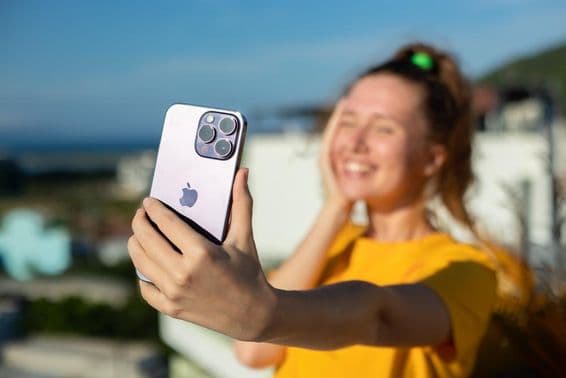 Mladé dievča drží iPhone telefón.