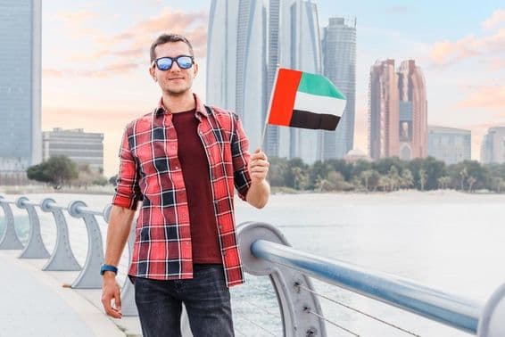 Mladý muž v Dubai Marina držiaci vlajku SAE.