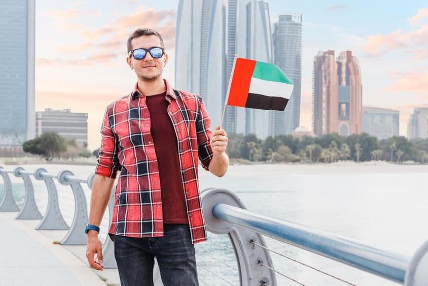 Mladý muž v Dubai Marina držiaci vlajku SAE.