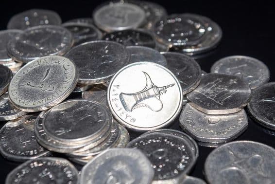 Hrsť mincí s hodnotou 1 dirham roztrúsených po povrchu.