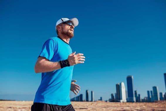 Dubaj Triatlon, muž beží s mrakodrapmi v pozadí.