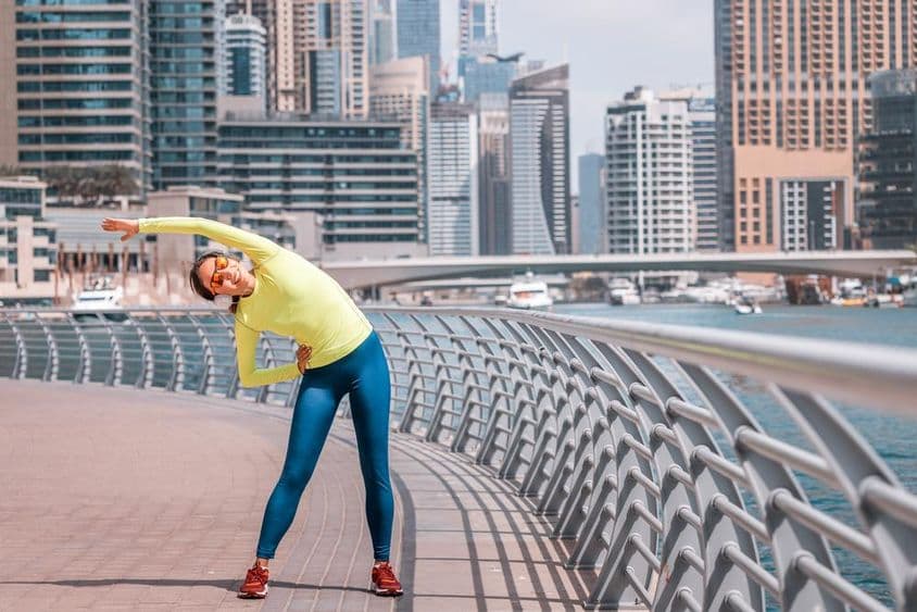 Dubajská mladá dievčina sa naťahuje po behu pri marine.