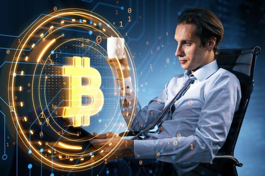 Biznismen s hrnčekom kávy sleduje cenu Bitcoinu.