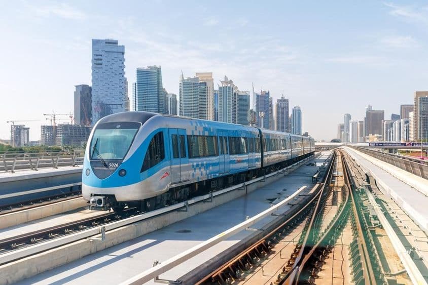 Dubajský metro vlak s budovami v pozadí.