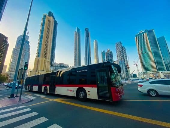 Autobus v Dubaji s mrakodrapmi v pozadí.