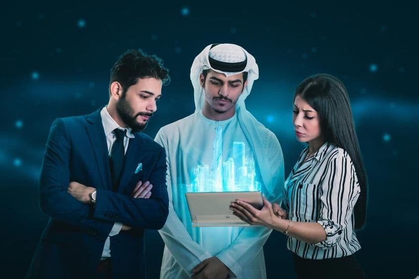 Dvaja muži a žena skúmajú hologram.