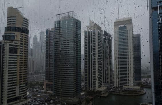 Detail mokrého okna ukazujúci moderný komerčný horizont Dubaja.