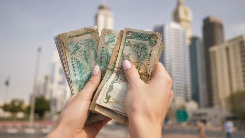 Dievča držiace menu UAE s výškovými budovami Dubaja v pozadí.