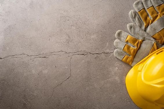 Čas na pauzu, žltá prilba a pracovné rukavice položené na popraskanej betónovej ploche.