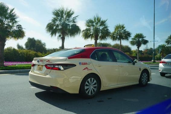 Dubajský taxík s červenou strechou jazdiaci po ceste.