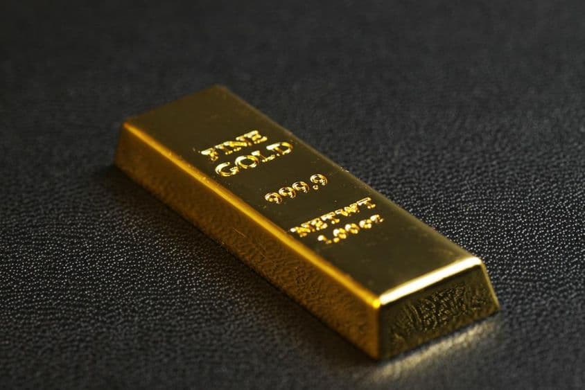 999,9 čistotné zlaté tehličky na čiernom pozadí.