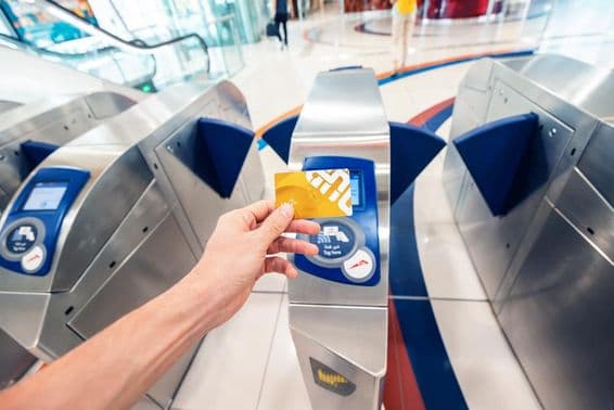 Mužský pasažier používa zlatú NOL kartu v Dubajskom metre na prechod cez turniket a cestovanie v prvom vagóne.