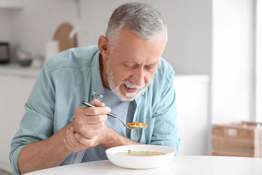 Starší muž s Parkinsonom, ako je pri kuchynskom stole.