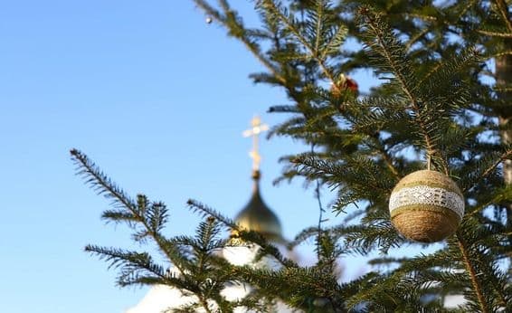 Vetvička vianočného stromčeka s ozdobami, s pravoslávnym krížom v pozadí
