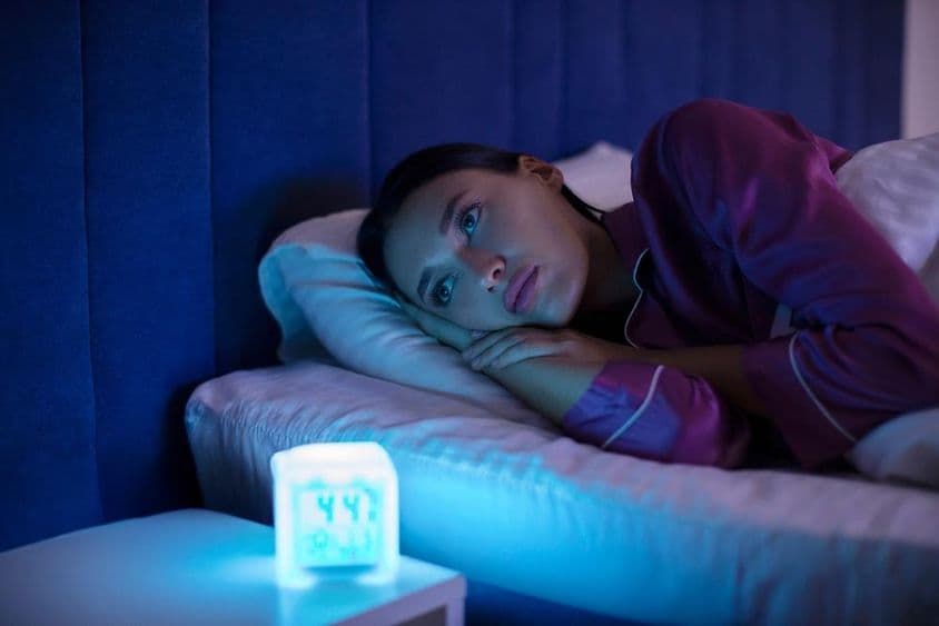 Smutná žena ležiaca v posteli, neschopná zaspať, trpiaca nespavosťou.