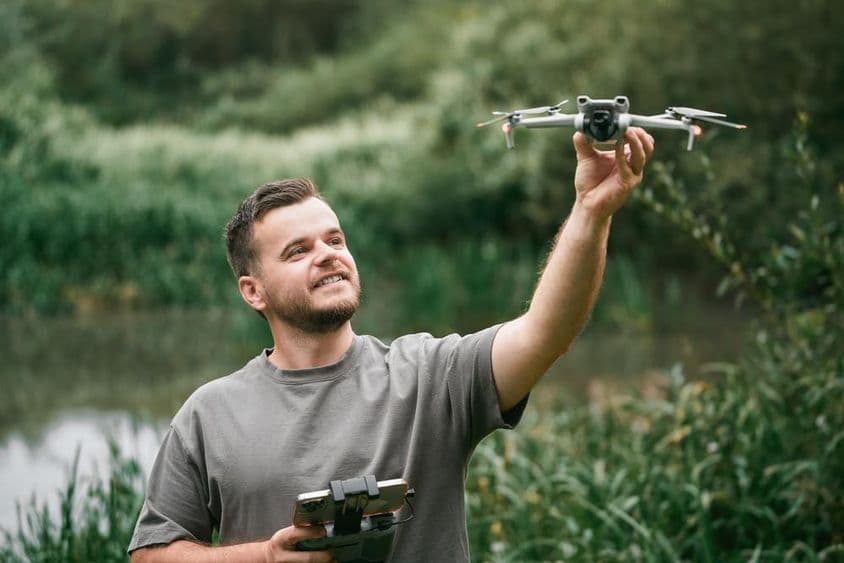 Inštruktor dronov s dronom v ruke počas vonkajšej hodiny.