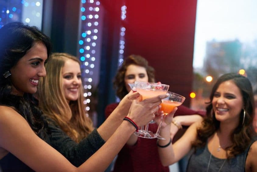 Dievčatá pripíjajú s drinkami v koktejlovom bare.