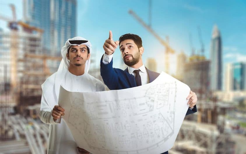 Architekt vysvetľujúci stavebný plán arabským stavbárom